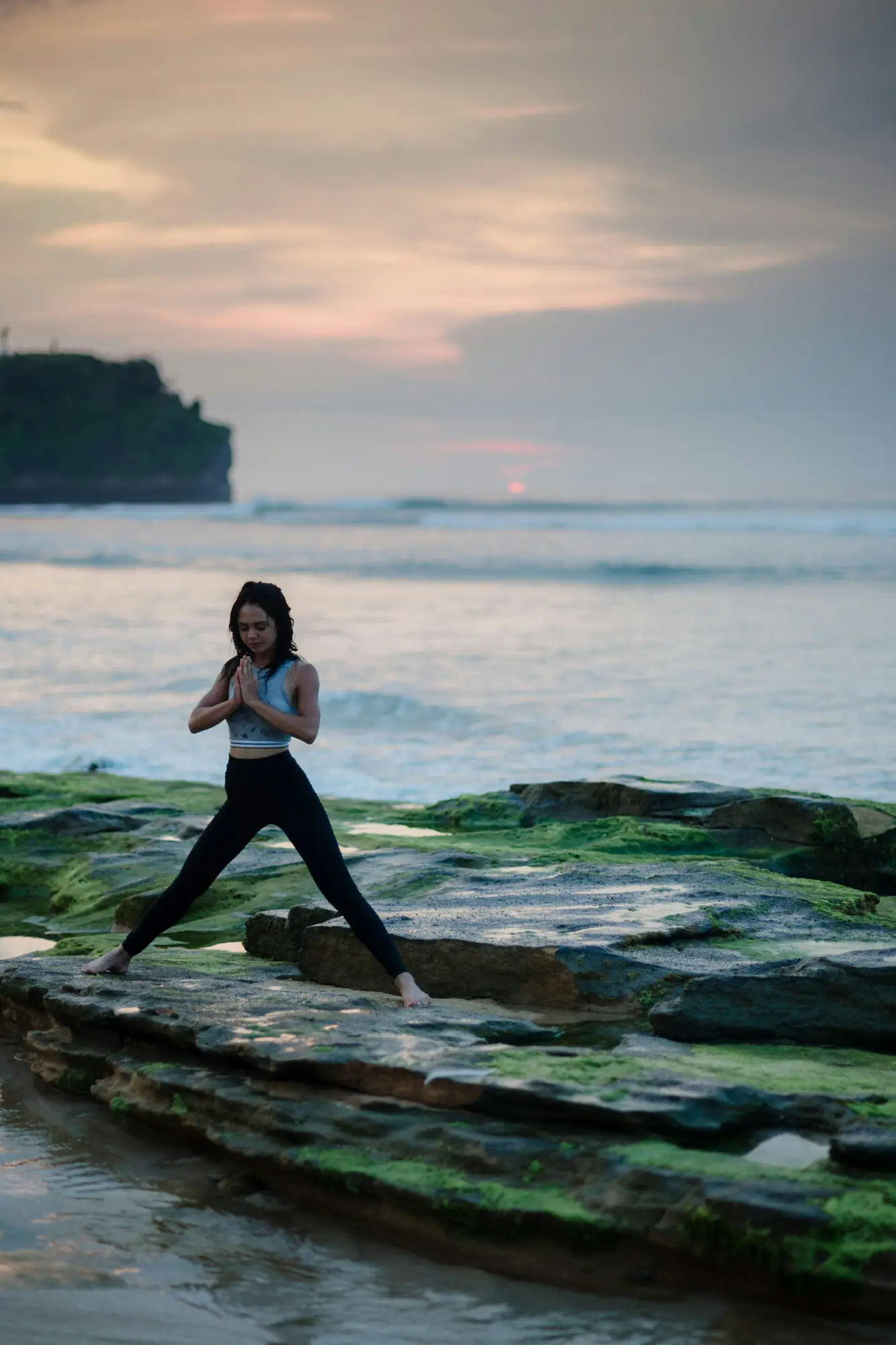 Femme en posture de yoga sur un rocher au bord de la mer